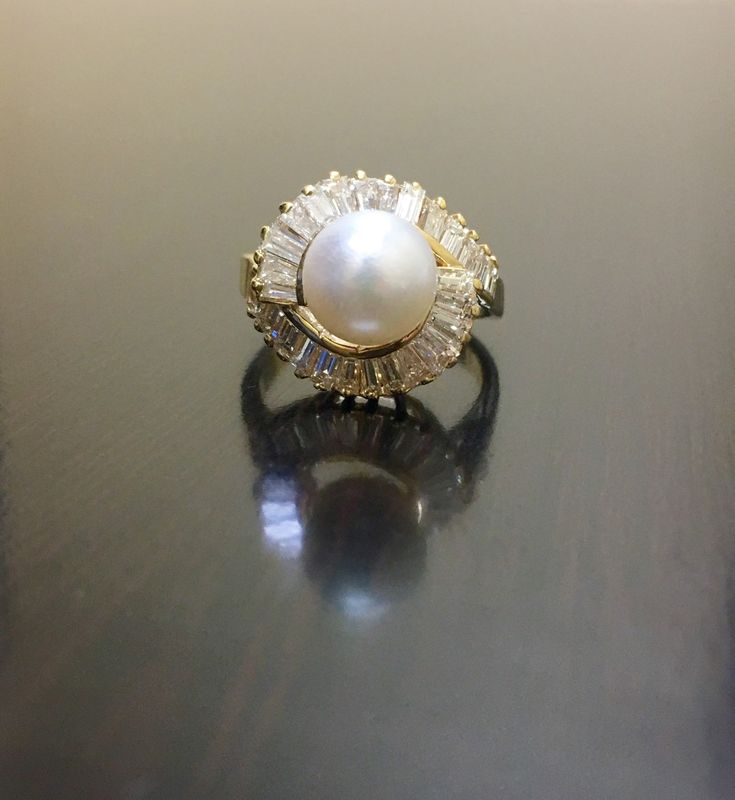 DeKara Designs Collection Beautiful Art Deco/Vintage/Modern Style Halo Diamond Pearl Cocktail Ring. Metal- 14K Yellow Gold, .583. Stones- 8 MM Round Tahitian/South Sea Pearl, 28 Baguette Diamonds G-H Color VS2 Clarity 1.20 Carats. A handmade truly magnificent 14K Yellow Gold Pearl Diamond Engagement Ring. There is a beautiful white pearl sitting in the center of the ring with elegantly set baguette diamonds that are dazzling surrounding the pearl. This ring is perfect! The diamonds are stunning Vintage White Diamond Ring With Halo Setting, Vintage White Pearl Ring With Brilliant Cut, Art Deco Cluster Ring With 17 Jewels, Vintage White Wedding Ring With Halo Setting, White Vintage Wedding Ring With Halo Setting, Classic Gold Halo Ring With Gemstone, Antique White Rings With Halo Setting, Vintage White Cluster Ring With Gemstone, Vintage White Rings With Halo Setting