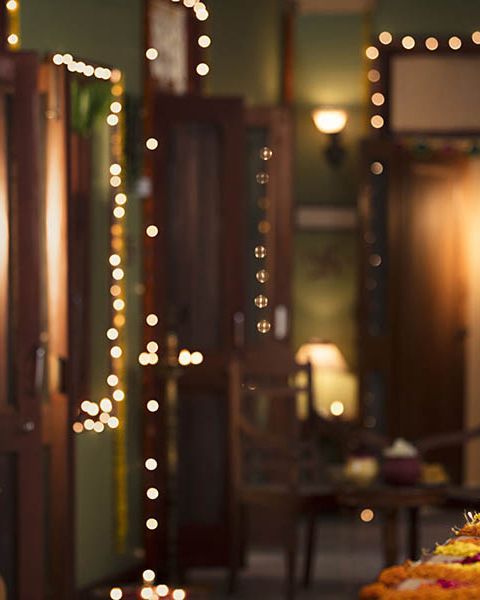 a table topped with lots of food covered in toppings next to a doorway filled with lights