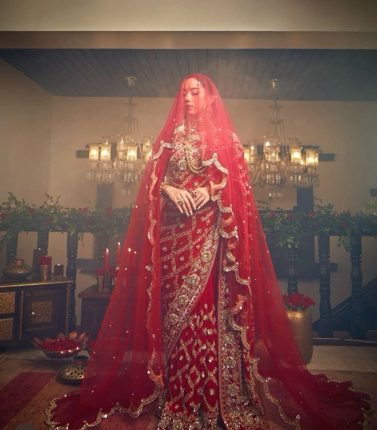 a woman in a red and gold bridal gown standing next to a chandelier