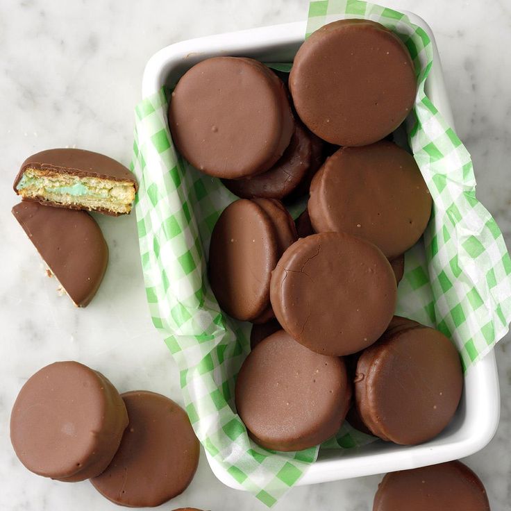 chocolate covered cookies in a white bowl on a marble counter top with green checkered napkins