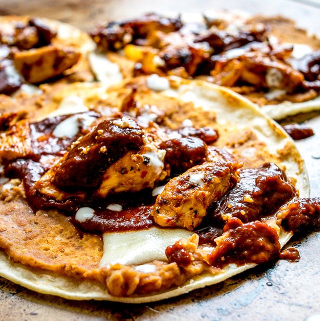 two tortillas covered in meat and sauce on top of a table with other food items