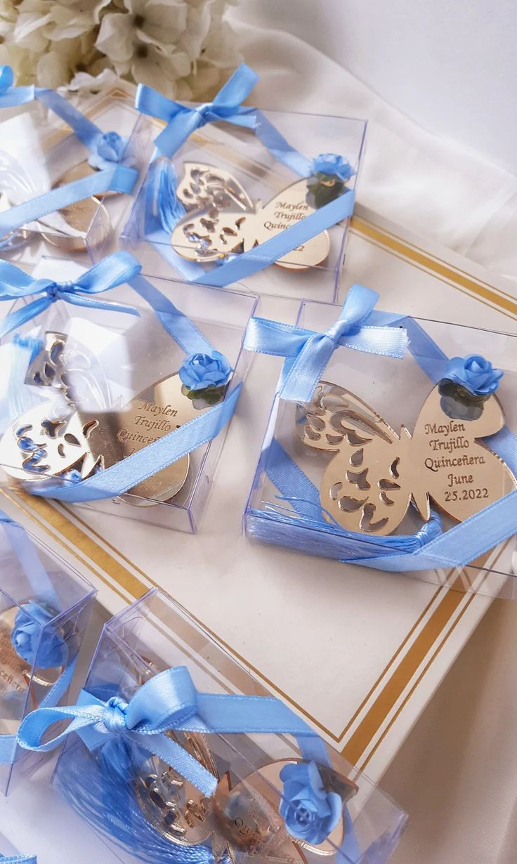 several small boxes filled with different types of cookies in blue ribbons and bows on top of a table