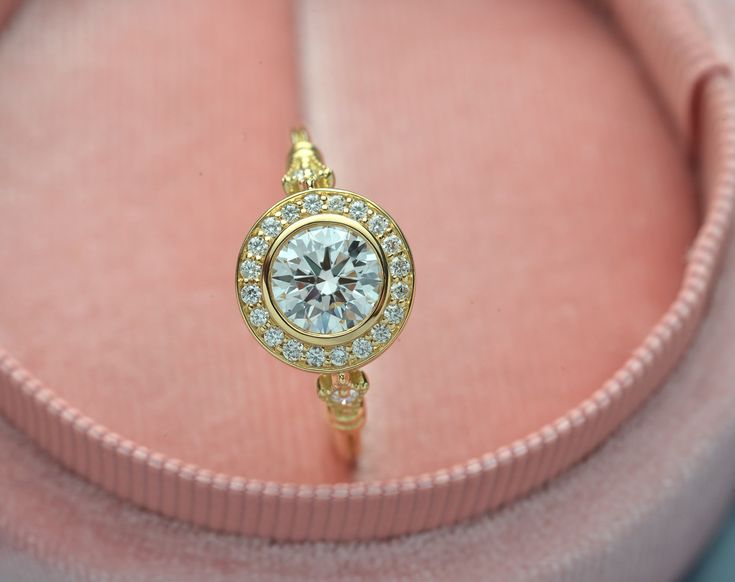 a close up of a ring on a pink velvet box with a diamond in the center