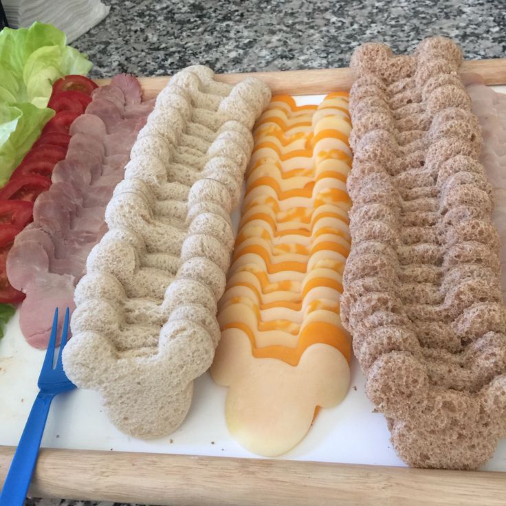 four hot dogs are lined up on a cutting board