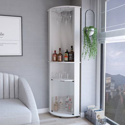 a white corner cabinet with wine glasses and bottles in it next to a window overlooking the city