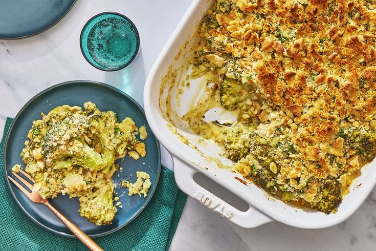 a casserole dish with broccoli and cheese on it next to two plates