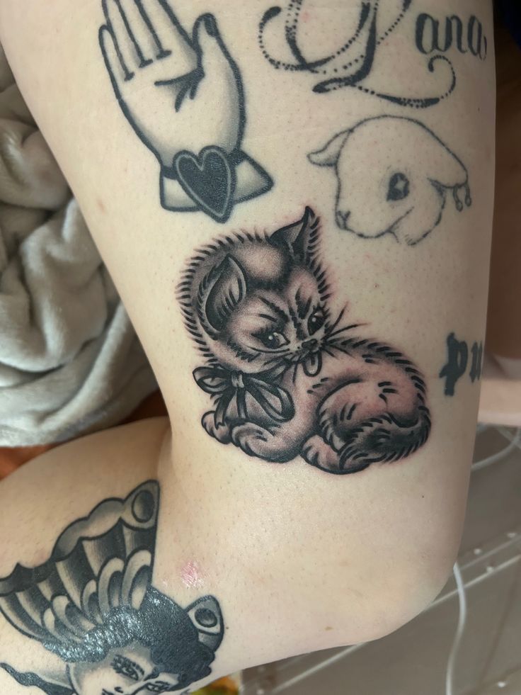 a woman's arm with tattoos on it and an image of a cat sitting in the middle