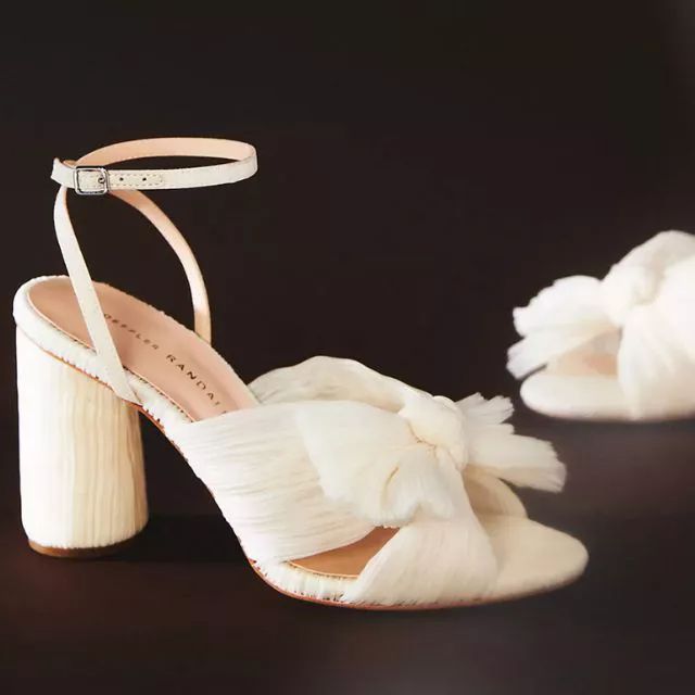 a pair of white high heeled shoes with flowers on the side and one in the middle