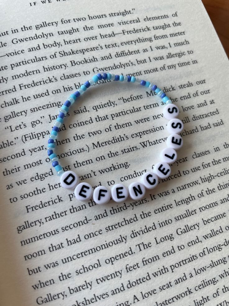 a bracelet with words written on it sitting next to an open page of a book