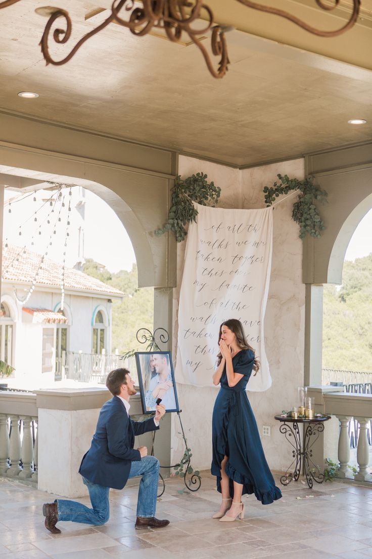 a man kneeling down next to a woman in front of a painting on a easel