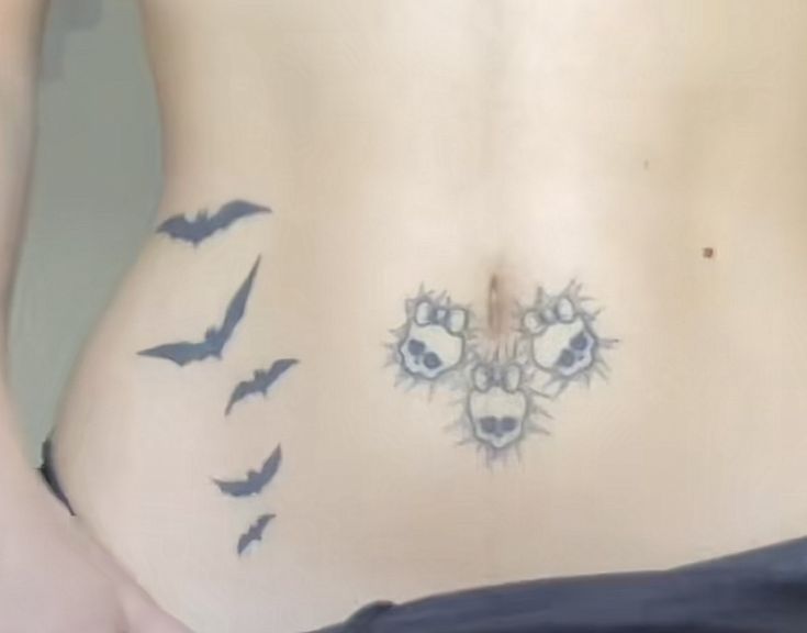 a woman's stomach with tattoos on it and birds flying over her bellys