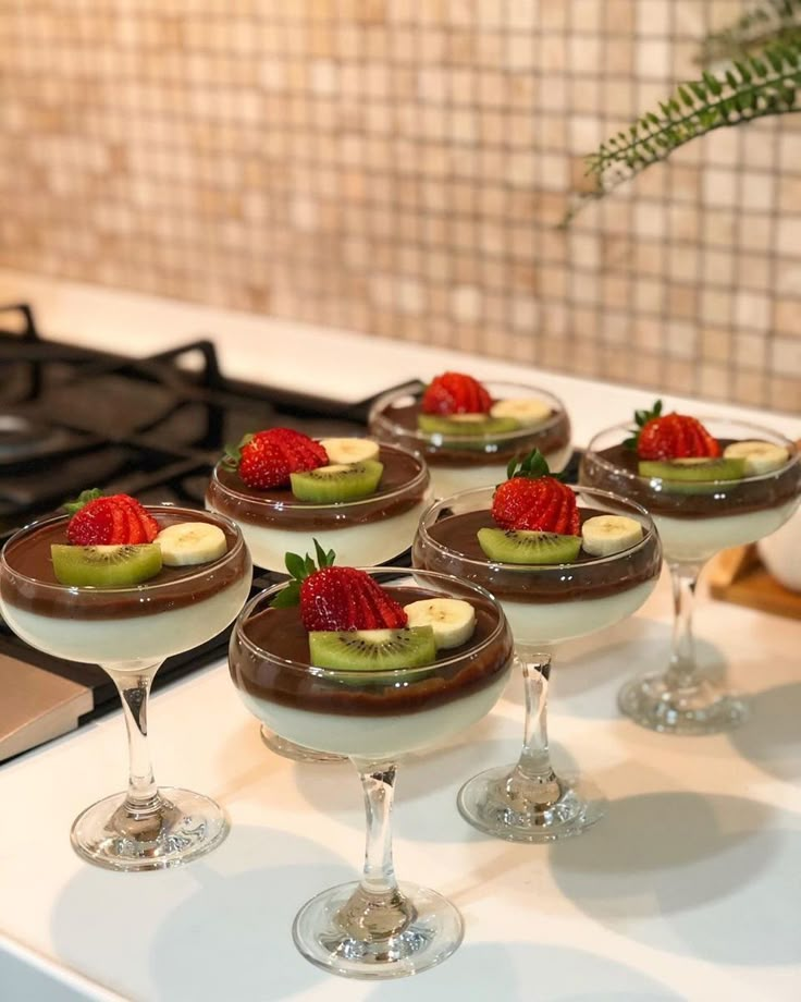 small desserts are arranged on the counter with chocolate sauce and strawberries in them