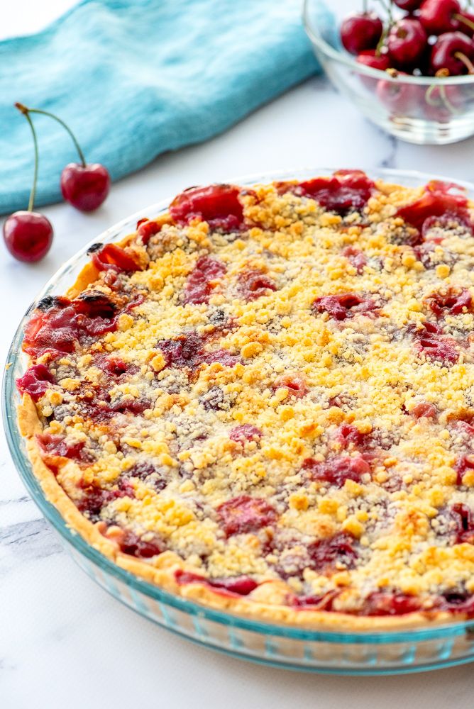 a pie sitting on top of a table next to a bowl of cherries