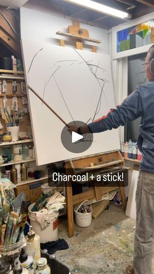 a man standing in front of a easel with a paintbrush on it's side