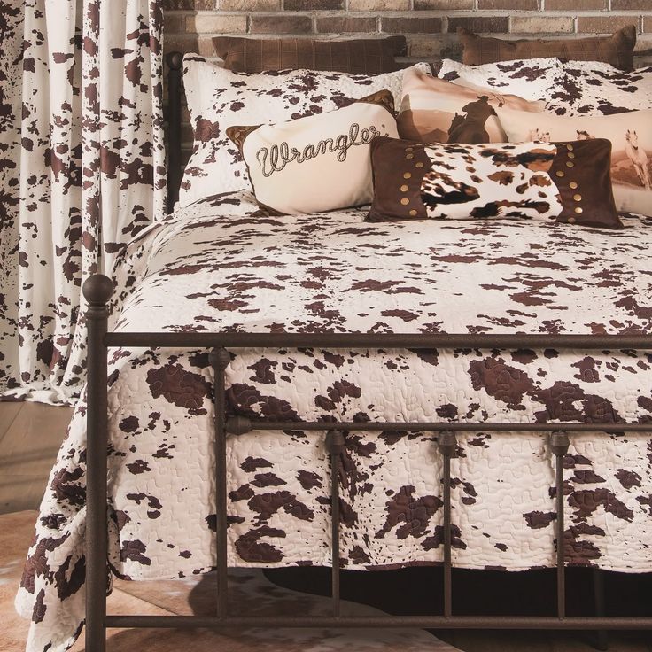 a bed with brown and white pillows on it's headboard, in front of a brick wall