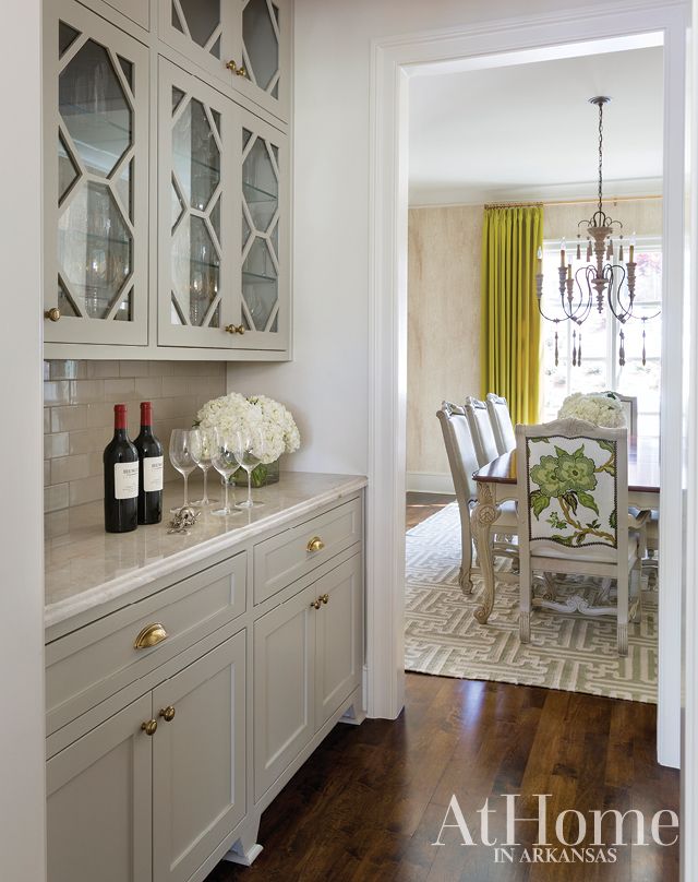 a dining room with white cabinets and wood floors