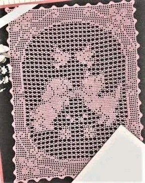 a pink crochet doily with flowers on it next to scissors and tape