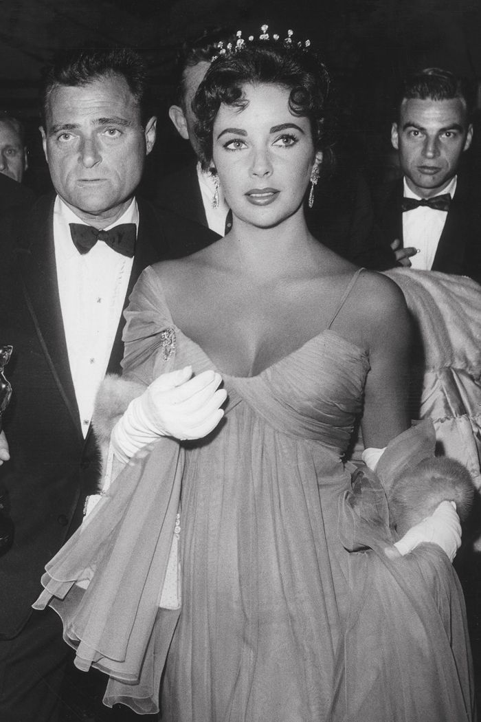 an old black and white photo of people in tuxedos holding their oscars