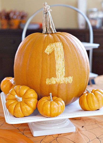 a pumpkin with the number one painted on it sitting on a white plate in front of other pumpkins