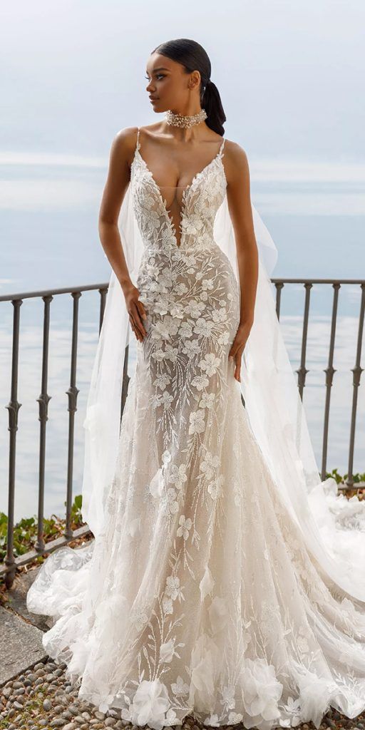 a woman in a wedding dress standing on top of a hill next to the ocean