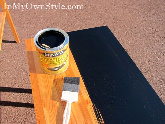 a can of paint sitting on top of a wooden table next to a black board