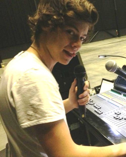 a young man holding a microphone in front of a sound board with an electronic keyboard on it