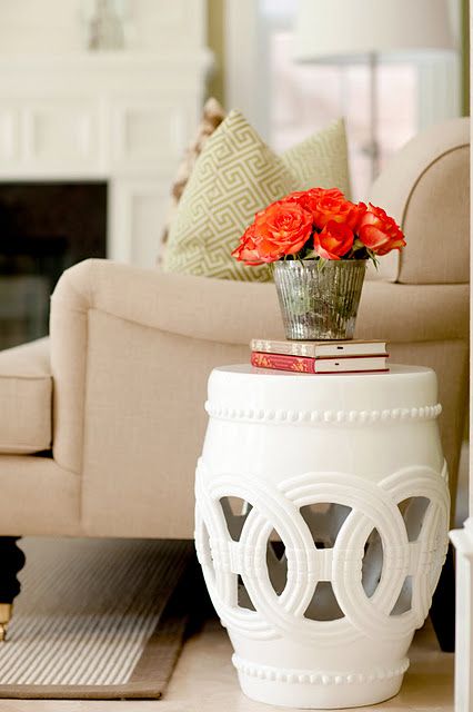 a white vase with red flowers on top of it sitting on a table in front of a couch