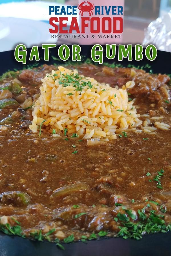 a close up of a plate of food with rice and meat on it in front of a sign that reads seafood restaurant & market gator gumbo