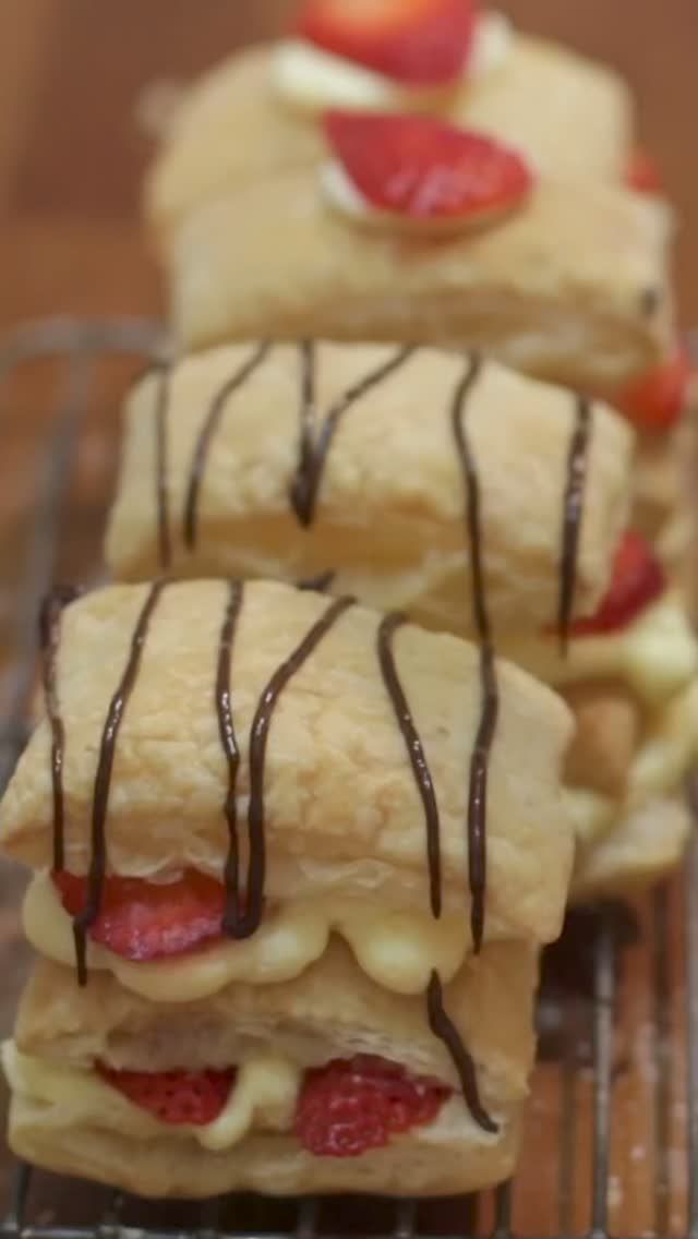 three pastries with chocolate drizzled on them sitting on a cooling rack