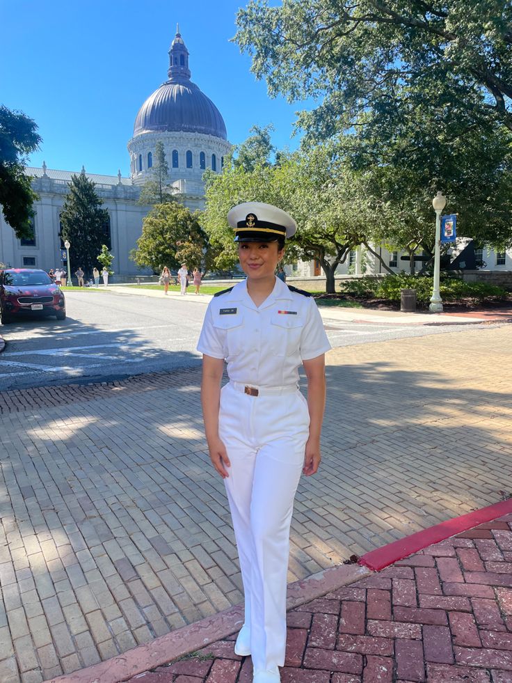 a woman in white uniform standing on the sidewalk