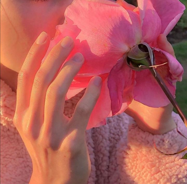 a woman holding a pink flower to her face