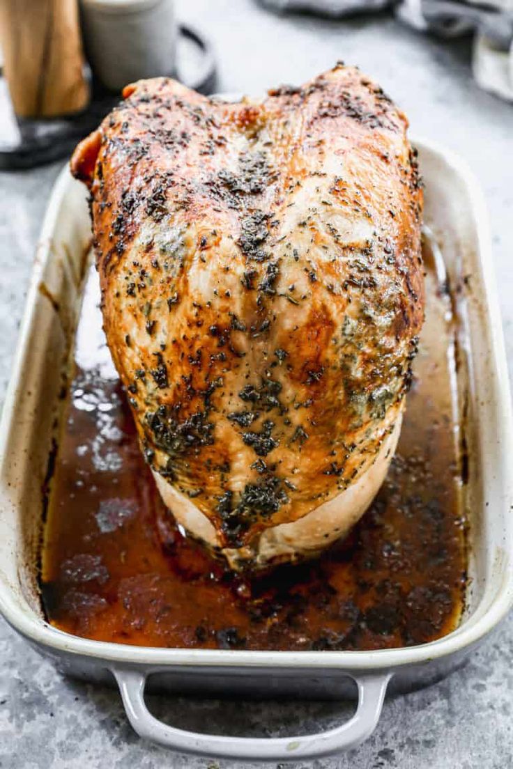 a close up of a chicken in a pan with sauce on the side and seasoning