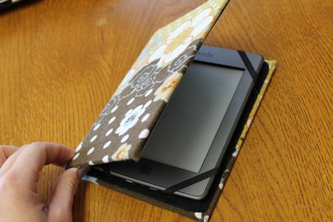 a person holding an electronic device on top of a wooden table