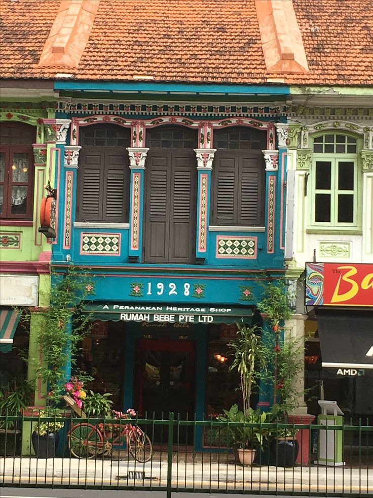 an old building with many windows and shutters on the outside, along side a fence