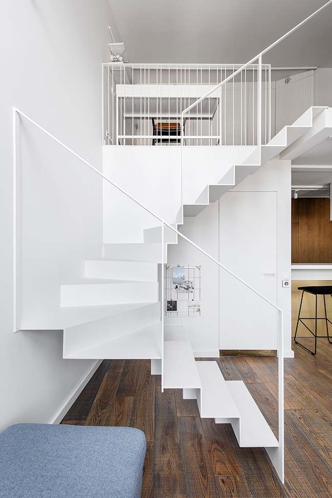 there is a white stair case in the room with wood flooring and blue chair