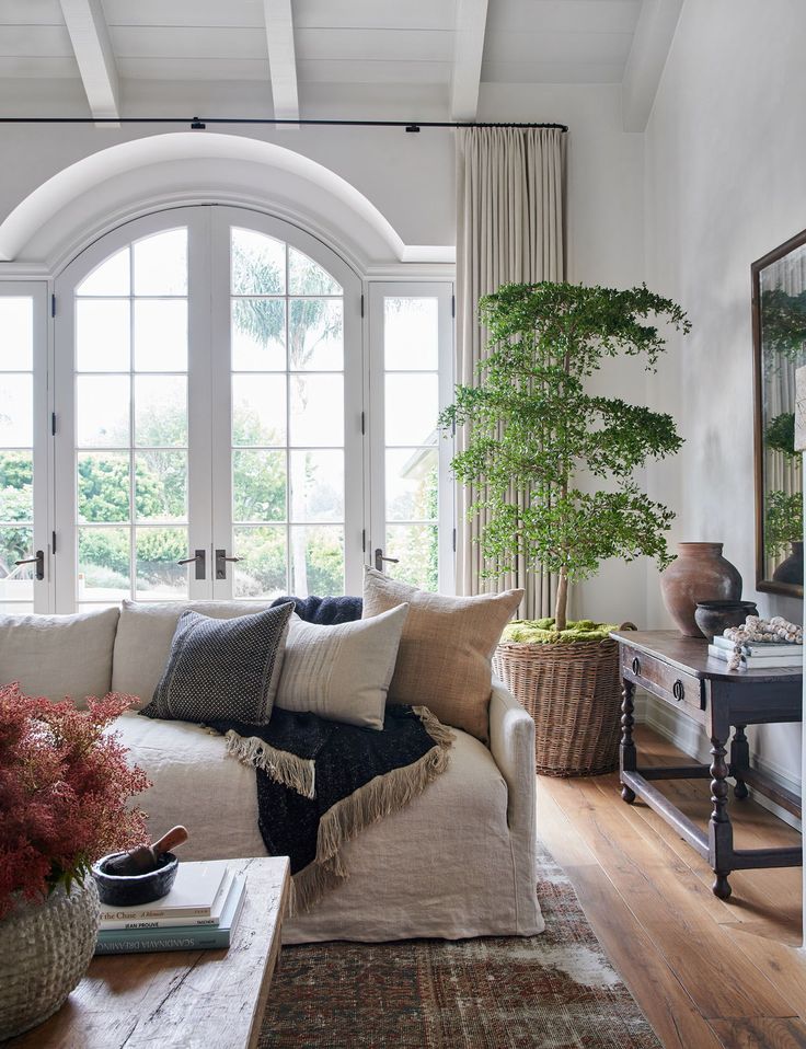 a living room filled with lots of furniture and plants on top of a wooden table