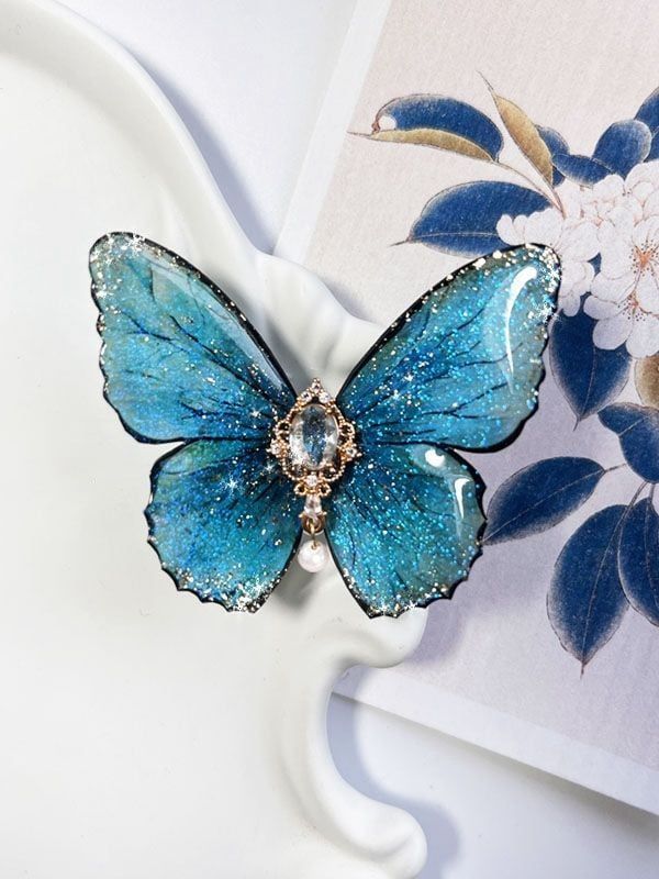 a blue butterfly brooch sitting on top of a white plate