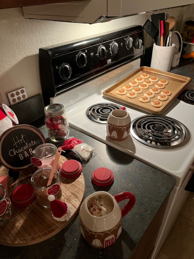 a stove top oven sitting next to a counter filled with cups and cookies on it