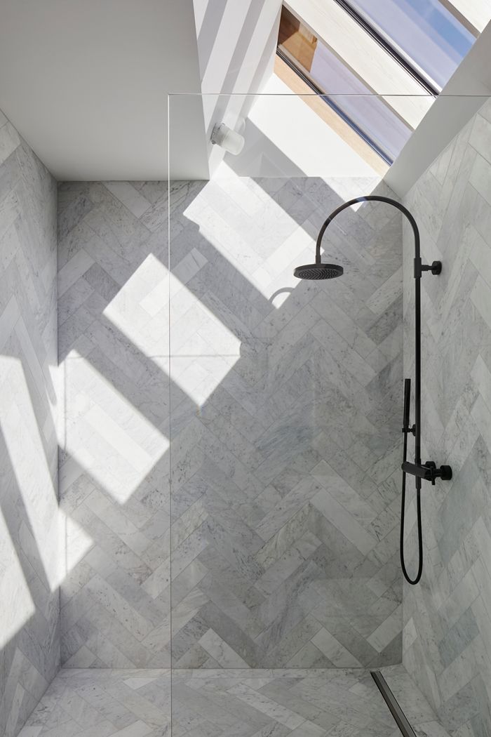 a bathroom with a skylight above the shower and tile flooring on the walls