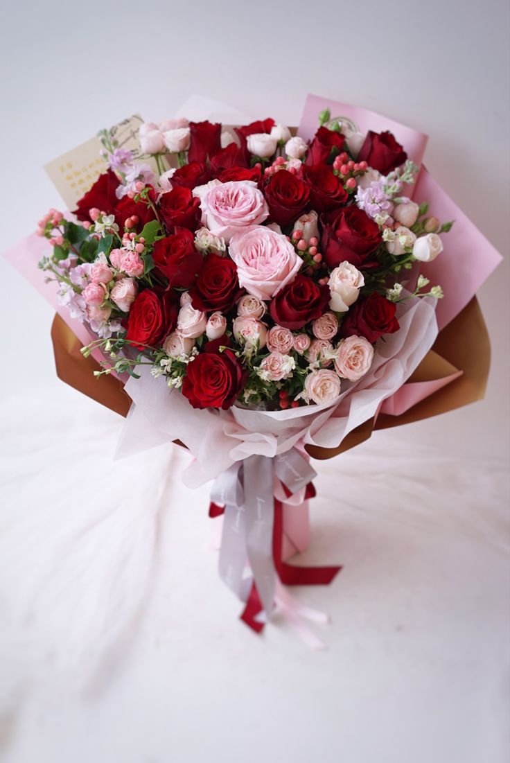 a bouquet of red, pink and white flowers on a white tableclothed surface