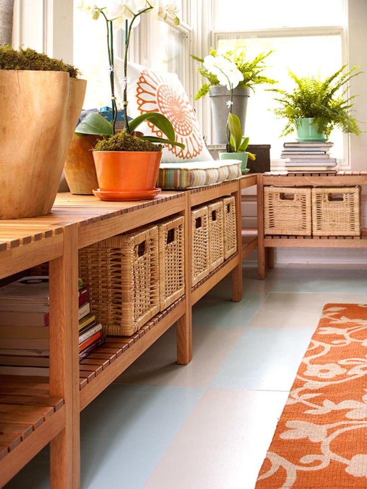 a living room filled with lots of plants on top of a wooden table next to a window