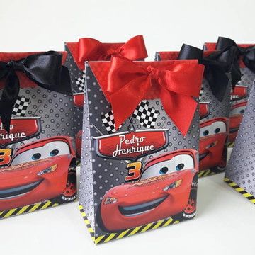 three bags with cars printed on them are lined up in front of each other, one has a red ribbon and the other is black