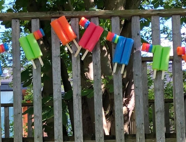 colorful popsicles hanging from clothes pins on a wooden fence