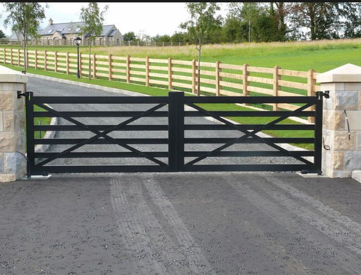 a gated driveway leading to a grassy field