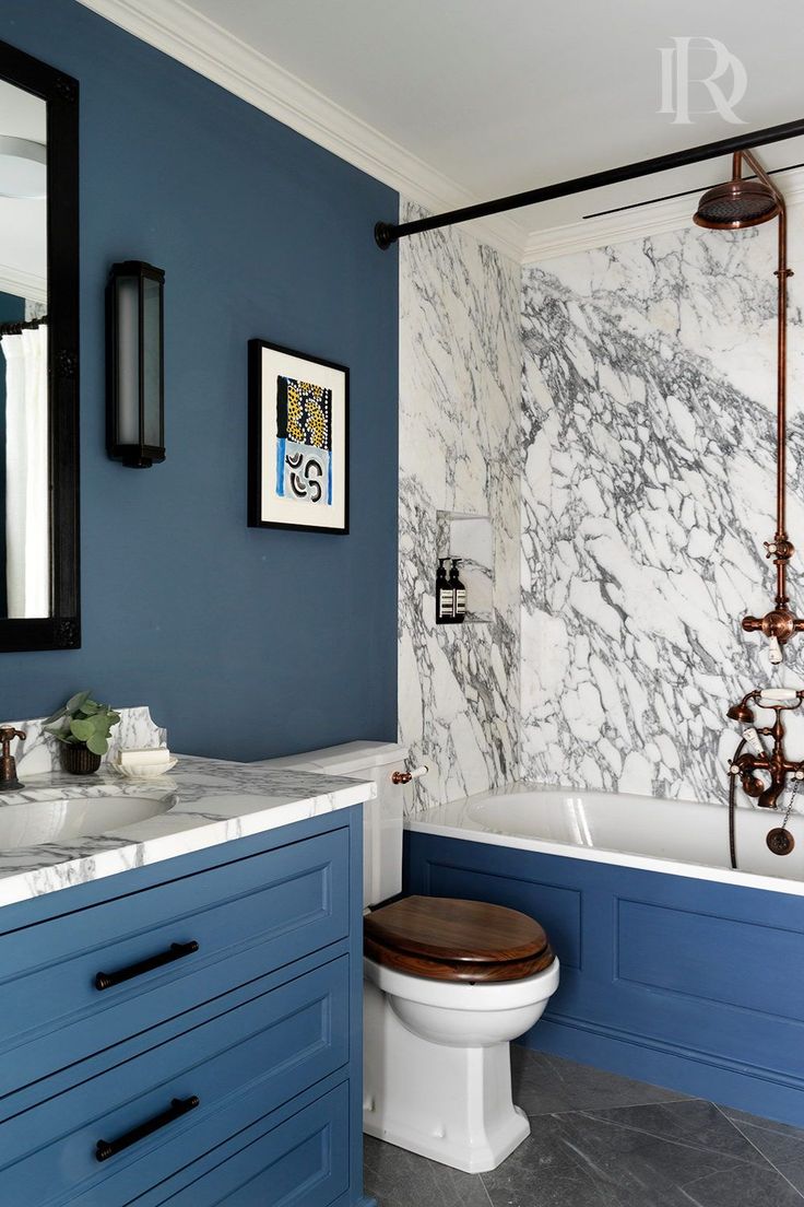 a bathroom with blue cabinets and marble walls