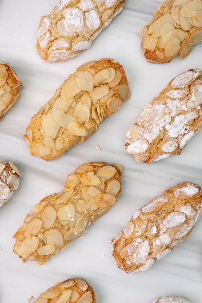 several pastries are arranged on a white surface with powdered sugar and almonds