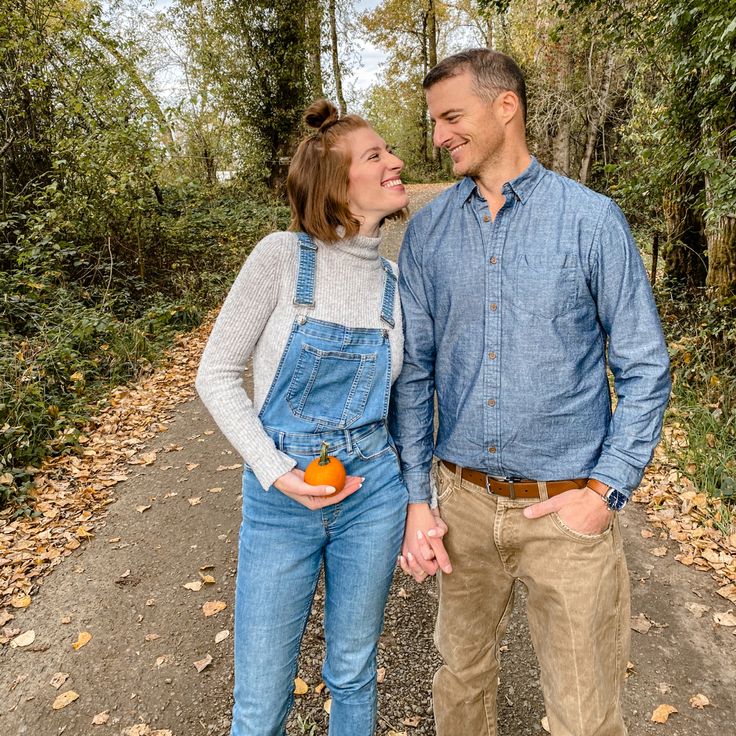 a man and woman standing next to each other on a dirt road