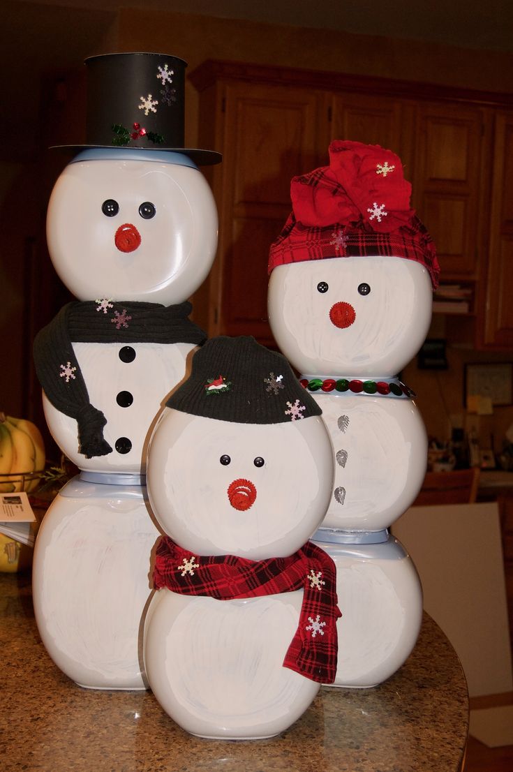 three snowmen with hats and scarfs on top of each other in front of a kitchen counter