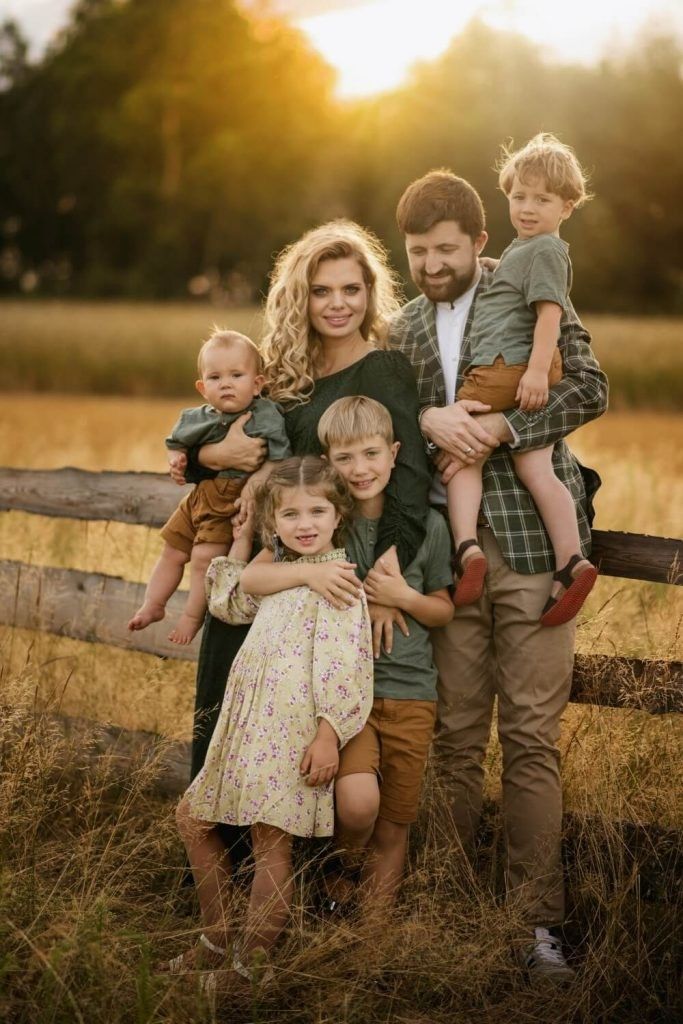 a family posing for a photo in front of a fence with the sun behind them