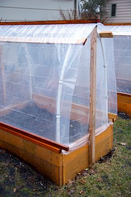 two small greenhouses with plastic covering over them